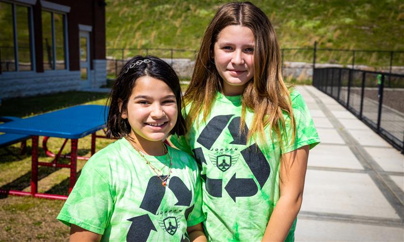 Two girls wearing Green Team t-shirts smile